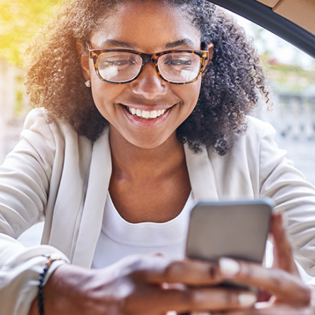 Mulher sorrindo olhando para seu smartphone